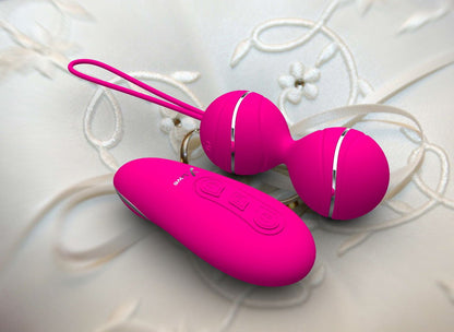 Bright pink vibrating balls and remote on white fabric