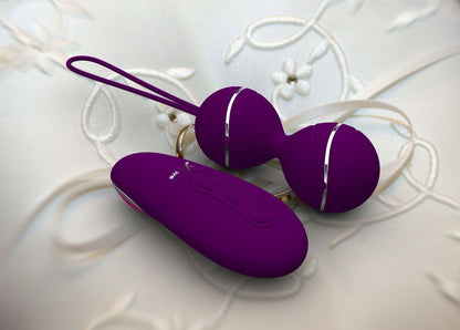 Purple vibrating balls and remote on white fabric